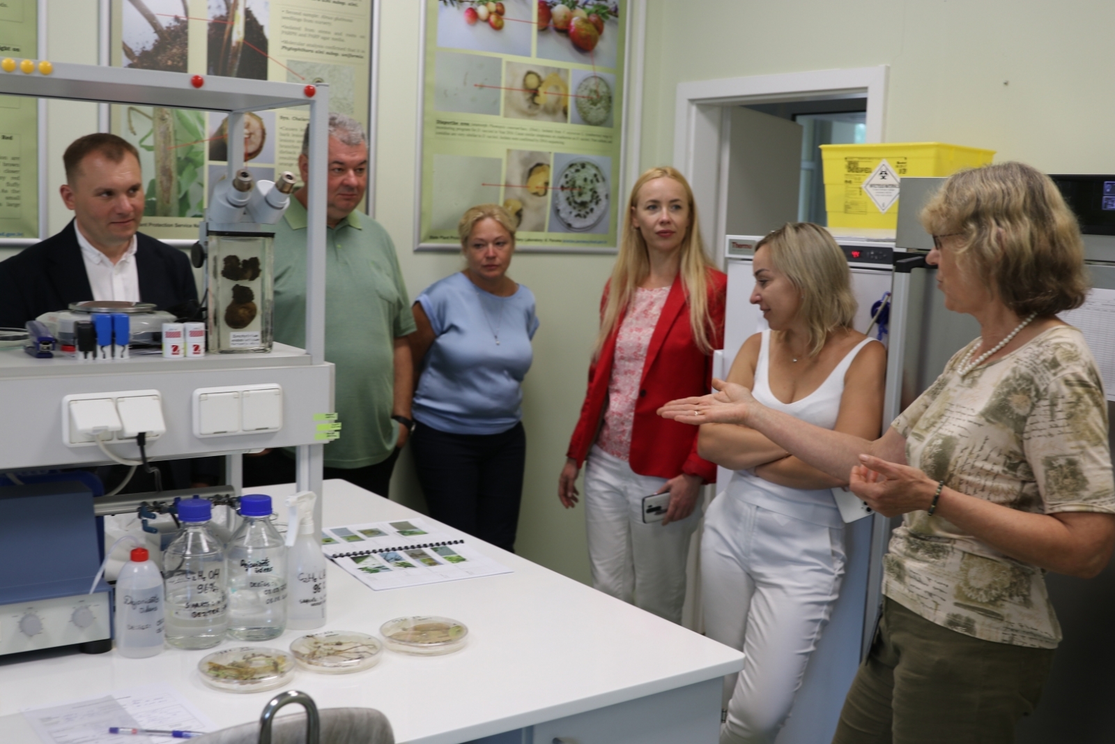 Nacionālā fitosanitārā laboratorija mikologu kabinetā, darbiniece stāsta Ukrainas kolēģiem